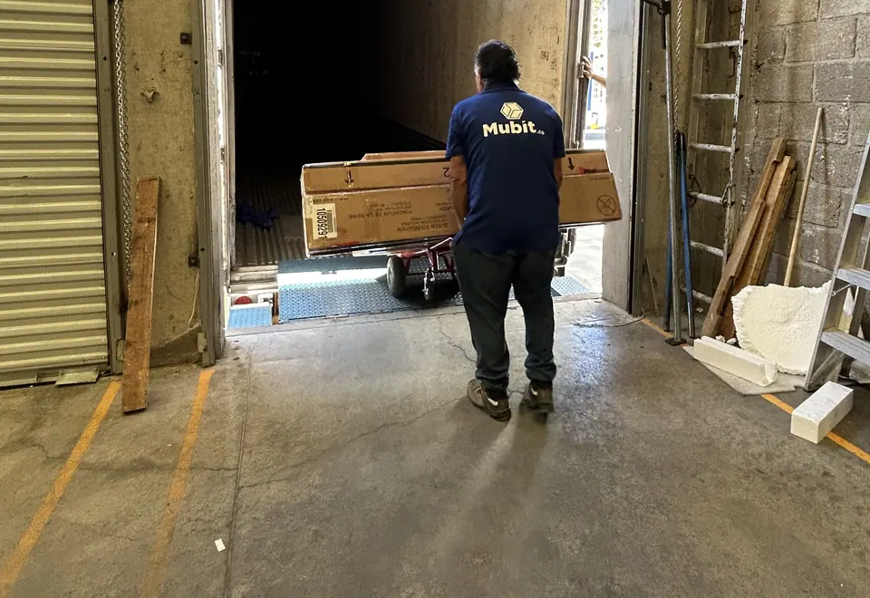 Operador de Mubit sacando una caja con diablo de un tráiler en el andén