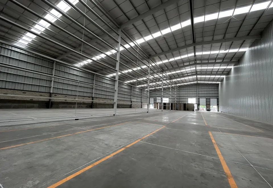 Nave amplia de piso liso con líneas de seguridad naranjas y estructura de acero, sin tarimas