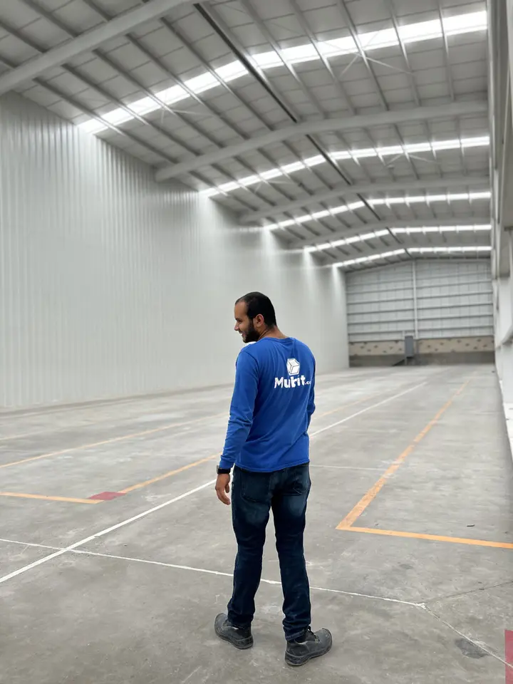 Operador de Mubit con uniforme azul de pie en una nave amplia de piso liso, para dar idea de la escala