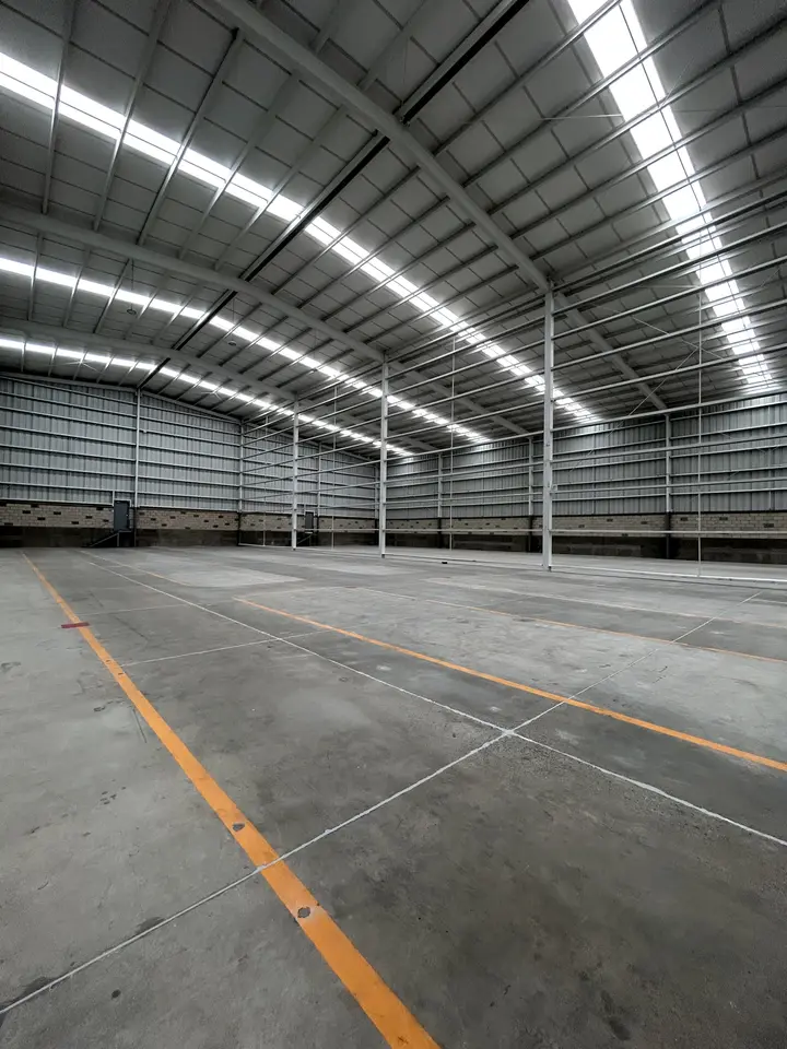 Piso de concreto con líneas naranjas de señalización dentro de una nave amplia